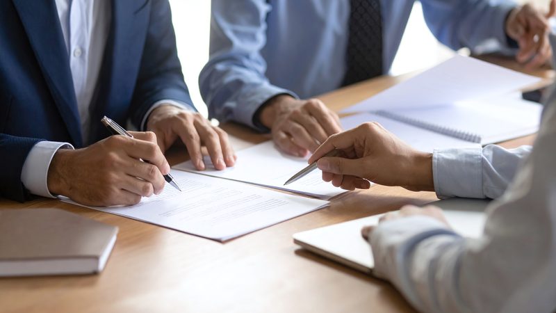 Business partners signing a contract at a desk, representing Commercial Contracts at KMT Solicitors