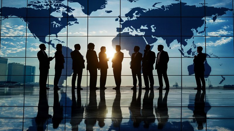 Executives silhouetted against a world map on a window, representing Shareholders, Partnerships and Joint Ventures at KMT Solicitors