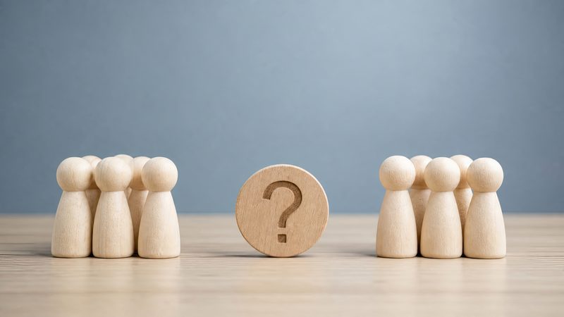 Two groups of wooden figures divided by a question mark, representing Alternative Dispute Resolution at KMT Solicitors