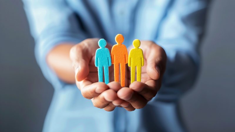 Hands holding small coloured figures of people, representing Employment Disputes at KMT Solicitors