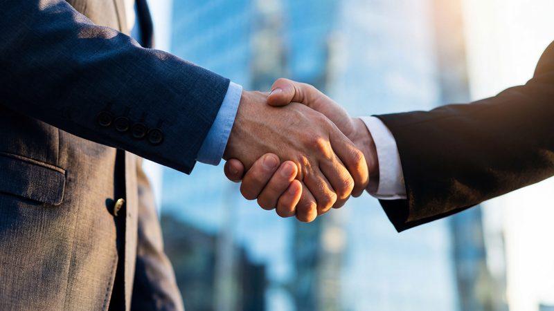 Business handshake in front of office buildings, representing Sponsor Licences and Worker Sponsorship at KMT Solicitors