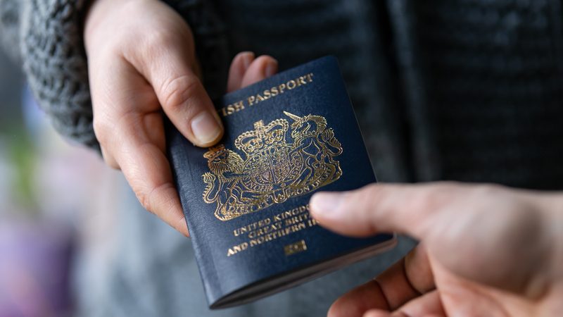 Blue British passport handed from one person to another, representing Visas and Entry Clearance at KMT Solicitors