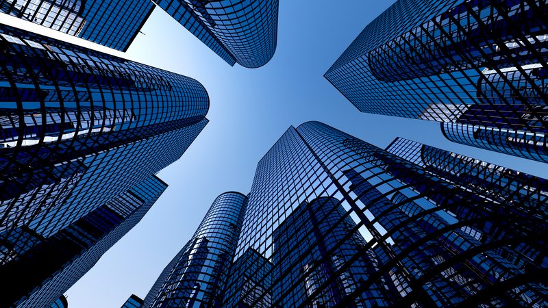 Modern glass office towers seen from below against a blue sky, representing Commercial Property at KMT Solicitors