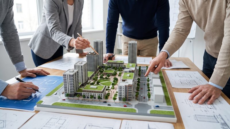 Professionals reviewing an architectural model of a development, representing Development and Planning at KMT Solicitors