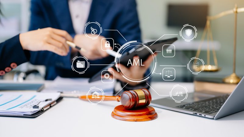 Business people at a desk with anti-money laundering icons, a gavel and scales, representing Anti-Money Laundering at KMT Solicitors