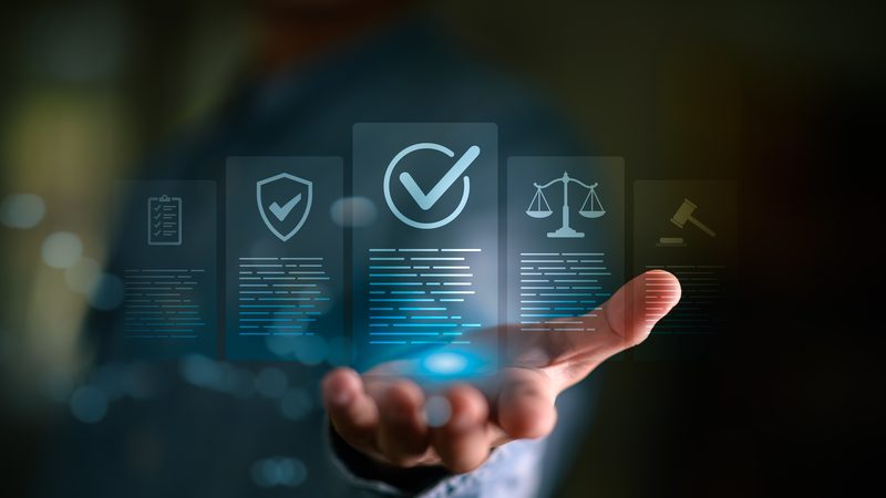 Hand holding governance and compliance icons, including a tick and scales, representing Corporate Governance and Compliance at KMT Solicitors