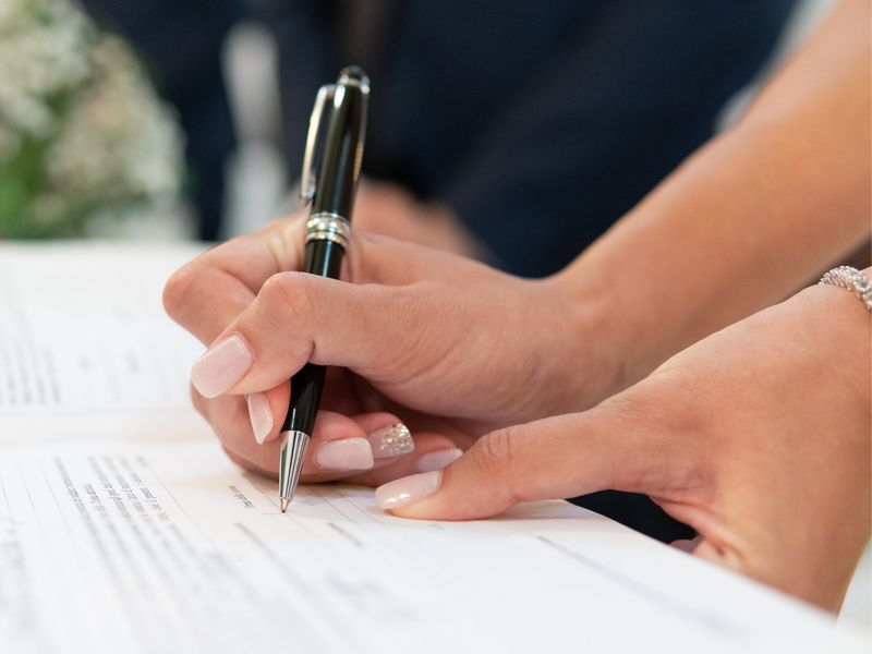 Signing a document with a pen, for fees and pricing at KMT Solicitors